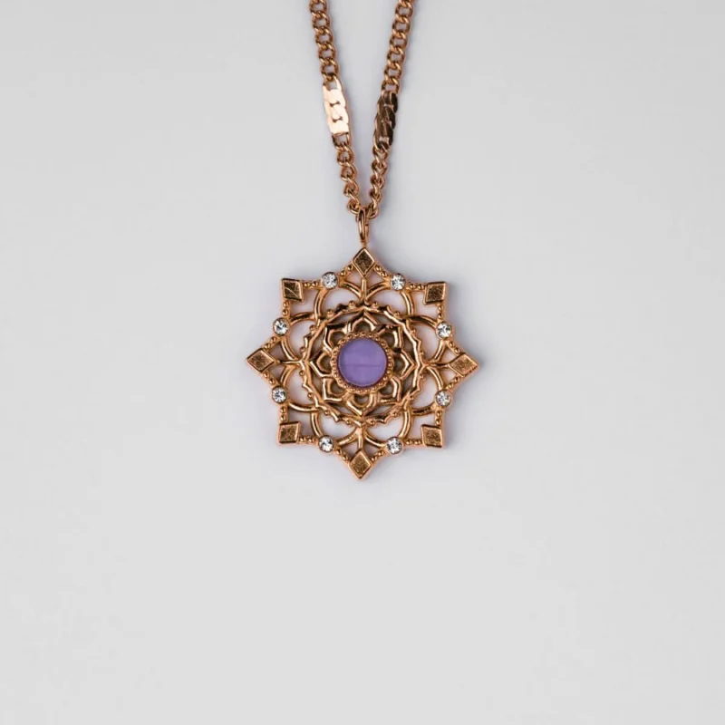 Goldfarbene Halskette mit rundem Anhänger und violettem Stein im Ornamentkranz