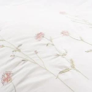 Close-up of ivory cotton bedding with delicate pink and sage embroidered wildflowers.
