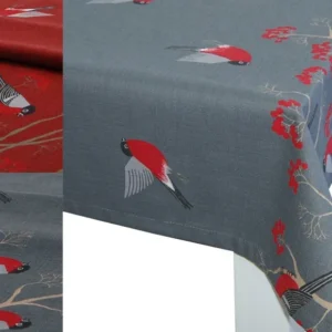 Ecke einer grauen Tischdecke, bedruckt mit rot-grau-schwarzen Voegeln. Teilweise fliegend und teilweise sitzen Sie auf Zweigen mit roten Beeren. Daneben ein Ausschnitt einer roten Tischdecke mit dem gleichen Motiv.