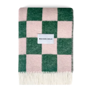 Green and pink checkerboard wool blanket folded with fringe detail