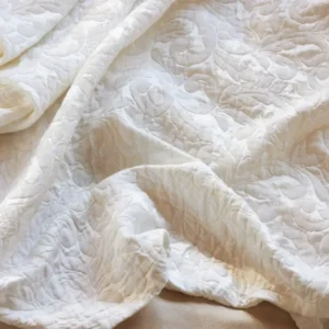 SDH Jasmine Matelassé sham in ivory, close-up of floral quilted texture and soft draping.